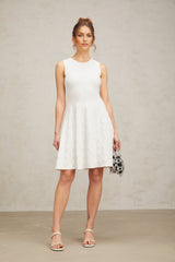 Young woman wearing a white mini dress with a jasmine star pattern knitted design