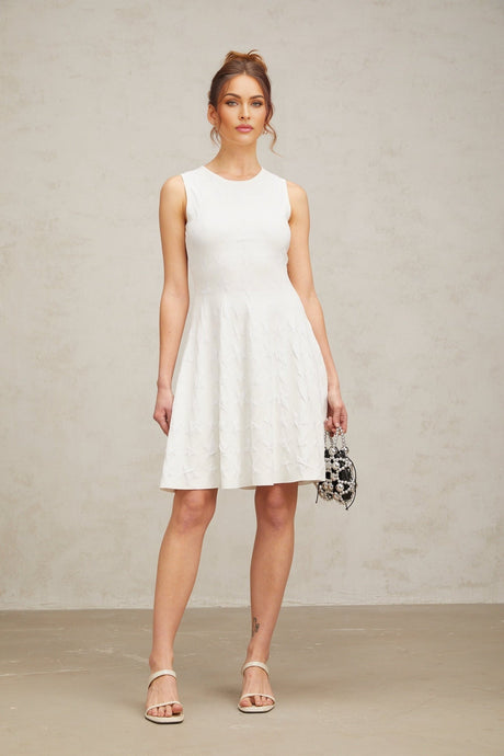 Young woman wearing a white mini dress with a jasmine star pattern knitted design