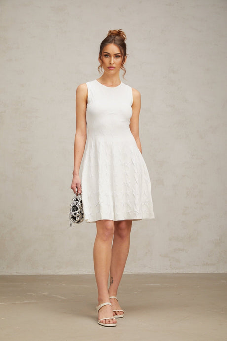Young woman wearing a white mini dress with a star pattern knitted design and jasmineinspired details