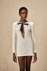 Young woman wearing a white mini dress with cutout details and a decorative bowknot feature