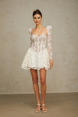 Young woman wearing a white mini dress with floral lace details and corset style bodice