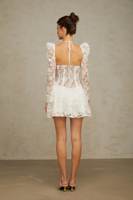 Young woman wearing a white mini dress with floral lace pattern and corset style bodice