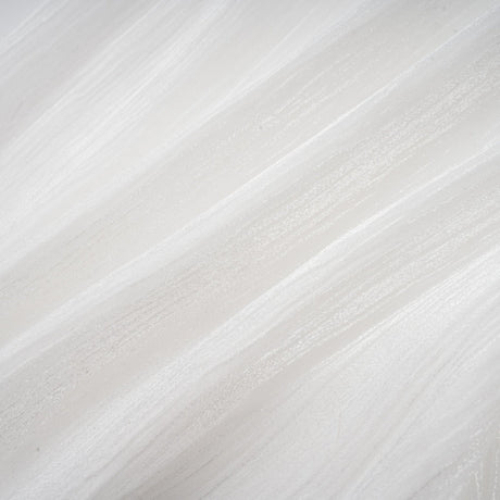 Young woman wearing a white mini dress with full pleats and cinched waist standing against plain background