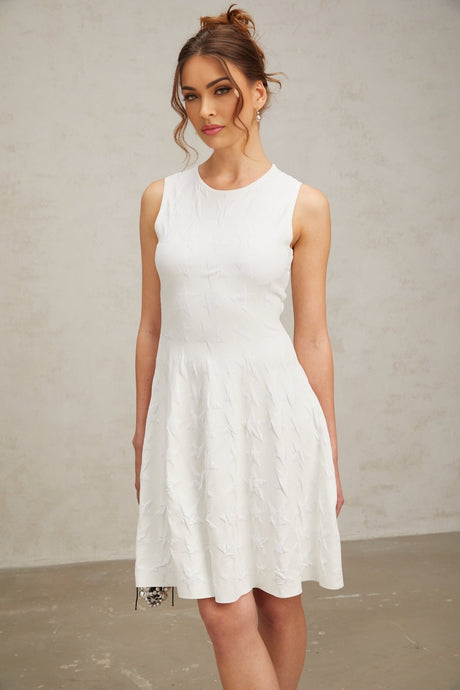 Young woman wearing a white mini dress with star pattern knit design and jasmine flower details