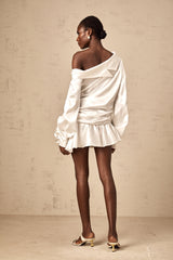 Young woman wearing a white satin mini dress with deconstructed design elements and asymmetrical details