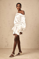 Young woman wearing a white satin mini dress with deconstructed design elements and asymmetrical styling