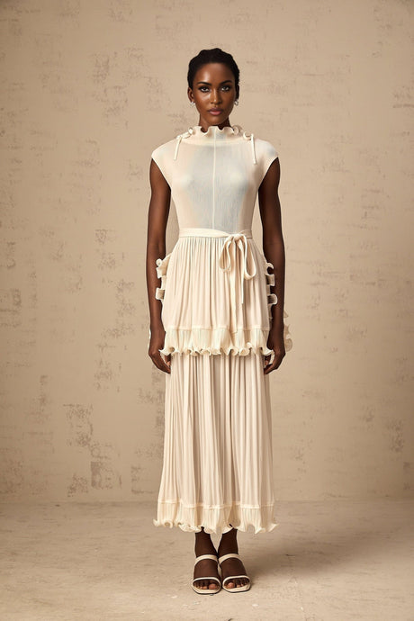 Young woman wearing a white sleeveless maxi dress with ruffle details and pleated skirt