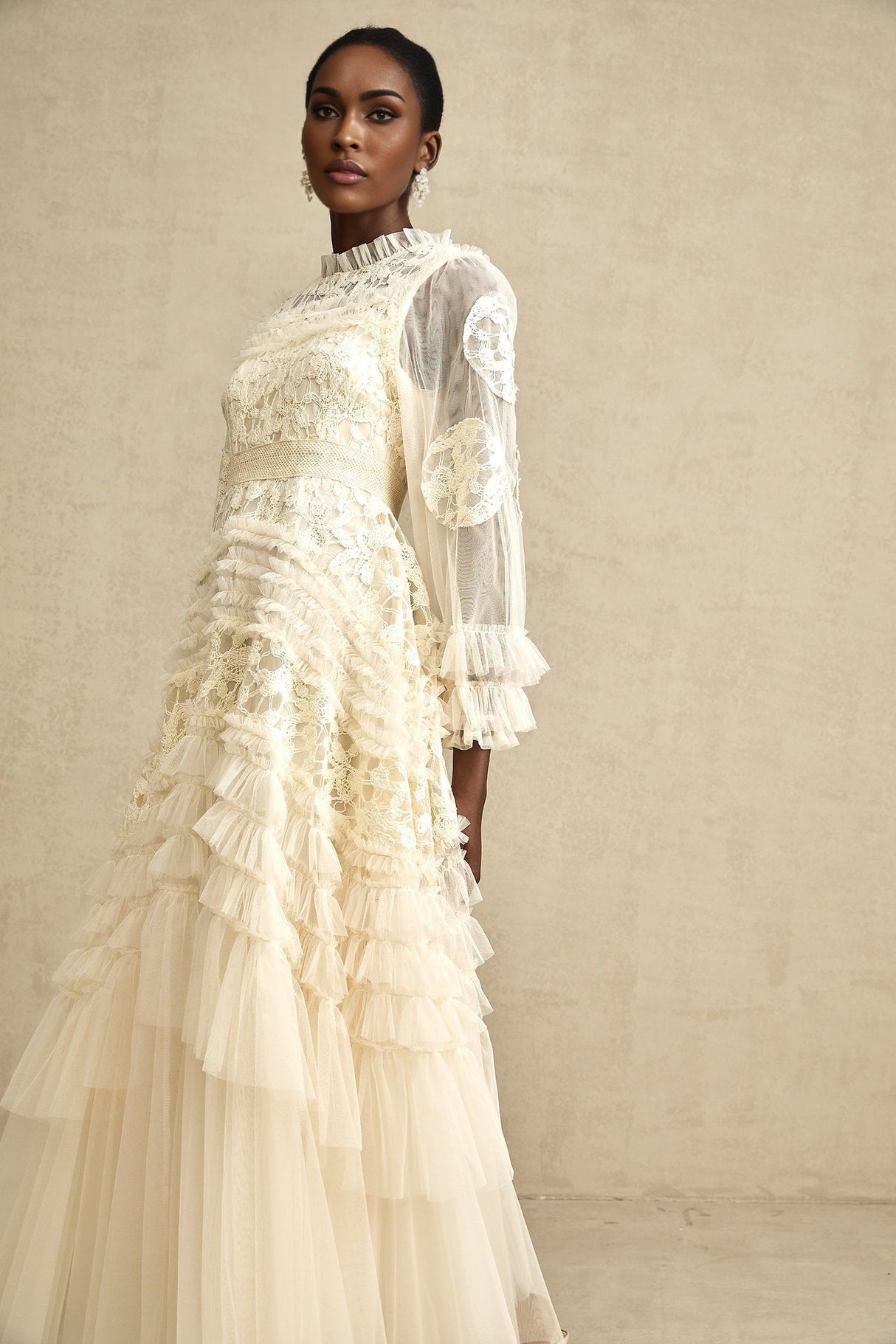 Young woman wearing long white tulle maxi dress with colorful floral embroidery and layered skirt design