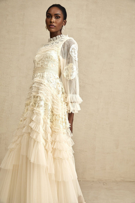Young woman wearing long white tulle maxi dress with colorful floral embroidery and layered skirt design